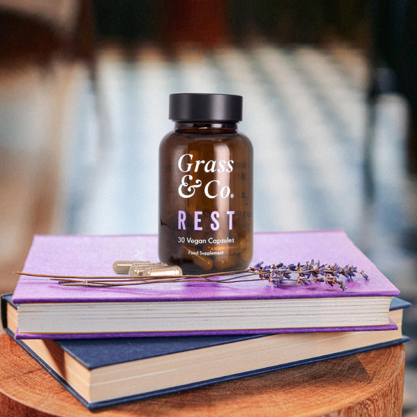 REST CBD capsules for sleep placed on 2 books.