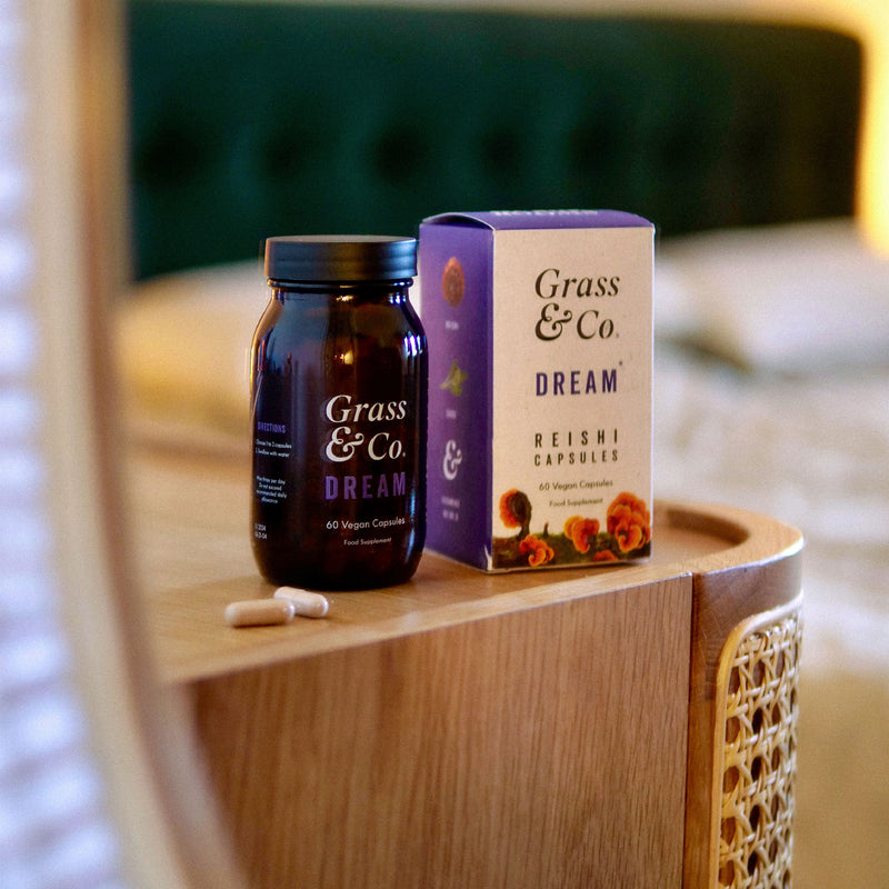 Packaging and bottle of Grass & Co.'s Reishi mushroom supplement capsules on a table.
