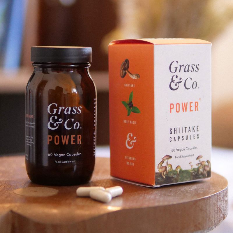 Packaging and bottle of Grass & Co.'s Shiitake mushroom supplement capsules on a table.